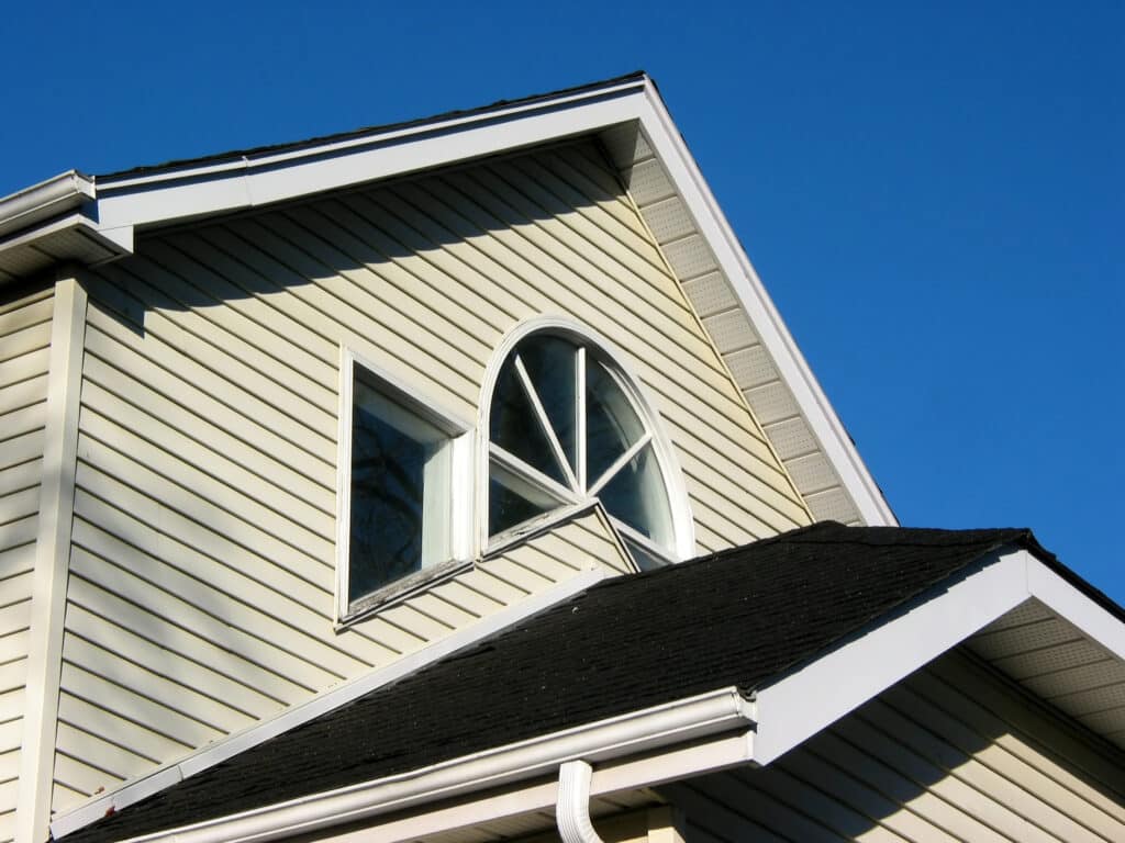 Fragment of a house on with bright blue sky. The Best Way to Clean Your Siding